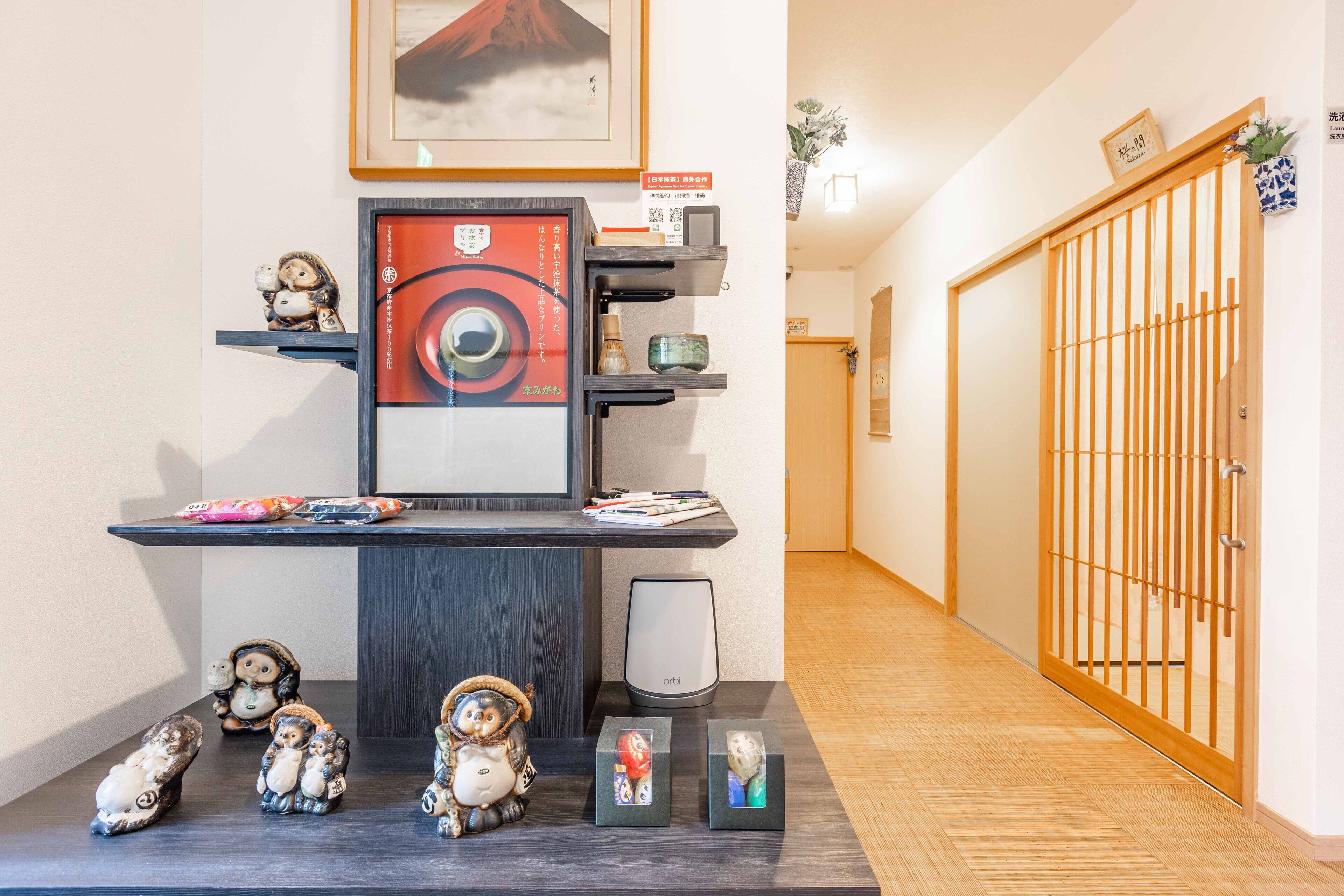 Un pasillo con un escritorio de madera oscura, un cuadro enmarco y una puerta corredera tradicional japonesa.