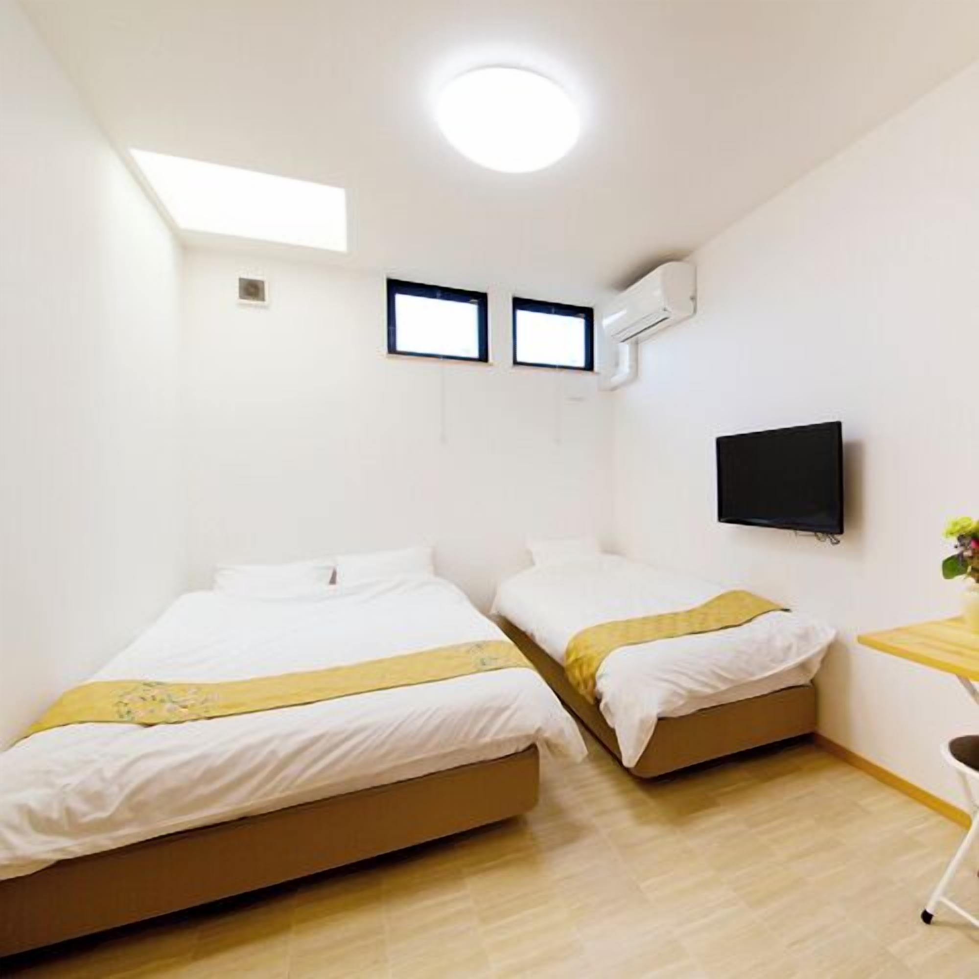 A hotel room with two beds, a TV, and a small desk with a chair.
