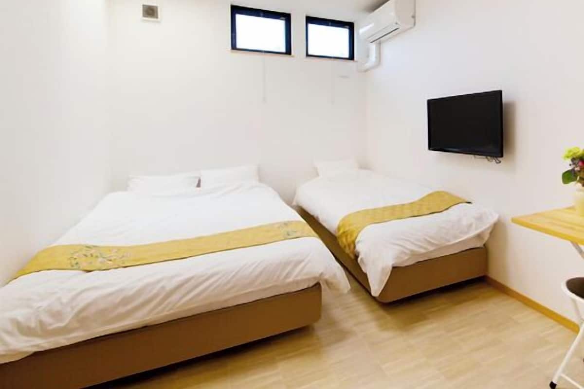 Habitación de hotel con dos camas, televisor y un pequeño escritorio con silla.
