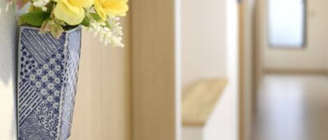 A hallway with a blue vase containing yellow flowers on the wall.