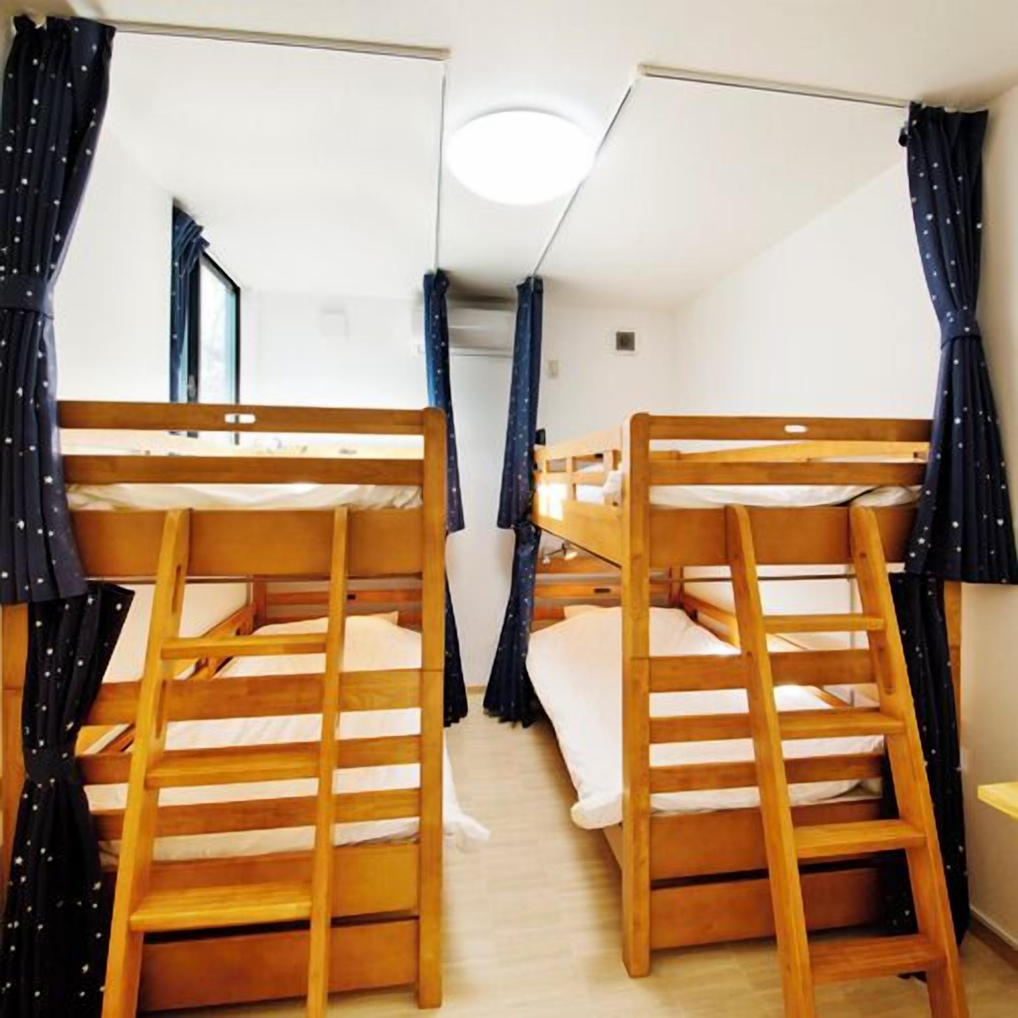 A bunk bed room with a ladder, curtains, and a window.
