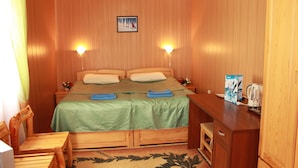 Een kamer met houten lambrisering, een bed, bedlampen, een bureau en een kast.
