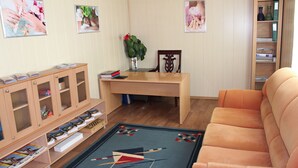 Een woonkamer met een bank, een houten tafel, een boekenkast en een kamerbreed tapijt met een patroon.