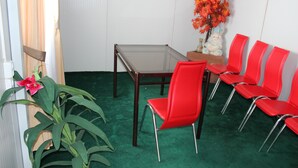Een kamer met een groen tapijt, een tafel met glazen blad en rode stoelen.