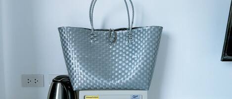 A silver woven bag on a scale next to a kettle and a digital safe.
