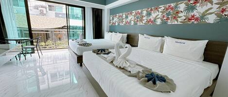 Una habitación de hotel con una cama grande, un balcón con vistas y una zona de comedor con mesa y sillas.