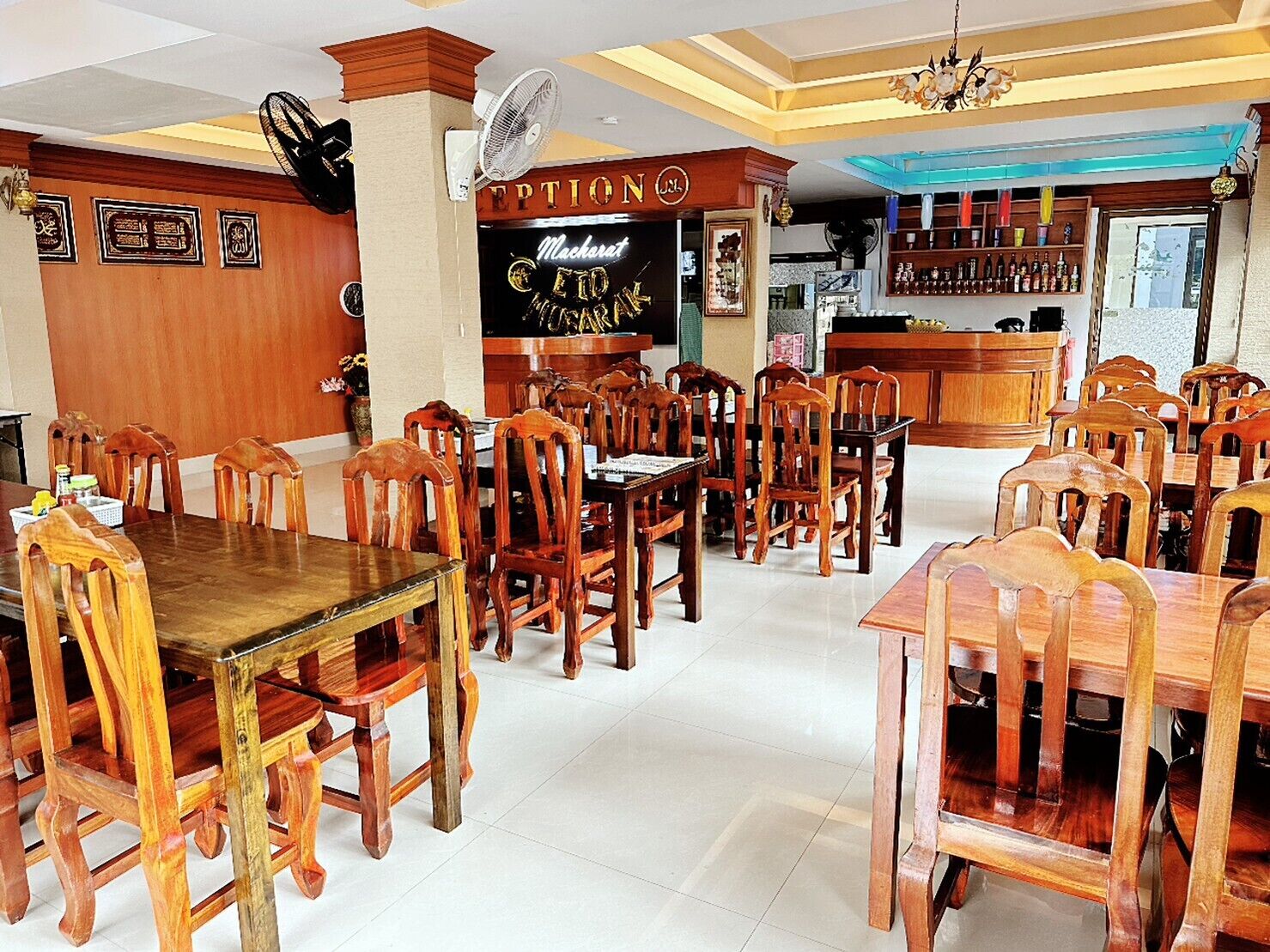 A restaurant with wooden tables and chairs, a bar area, and a ceiling fan.