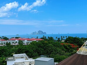 A coastal view with buildings, palm trees, and a clear sky. - Machorat Aonang Resort (Krabi)