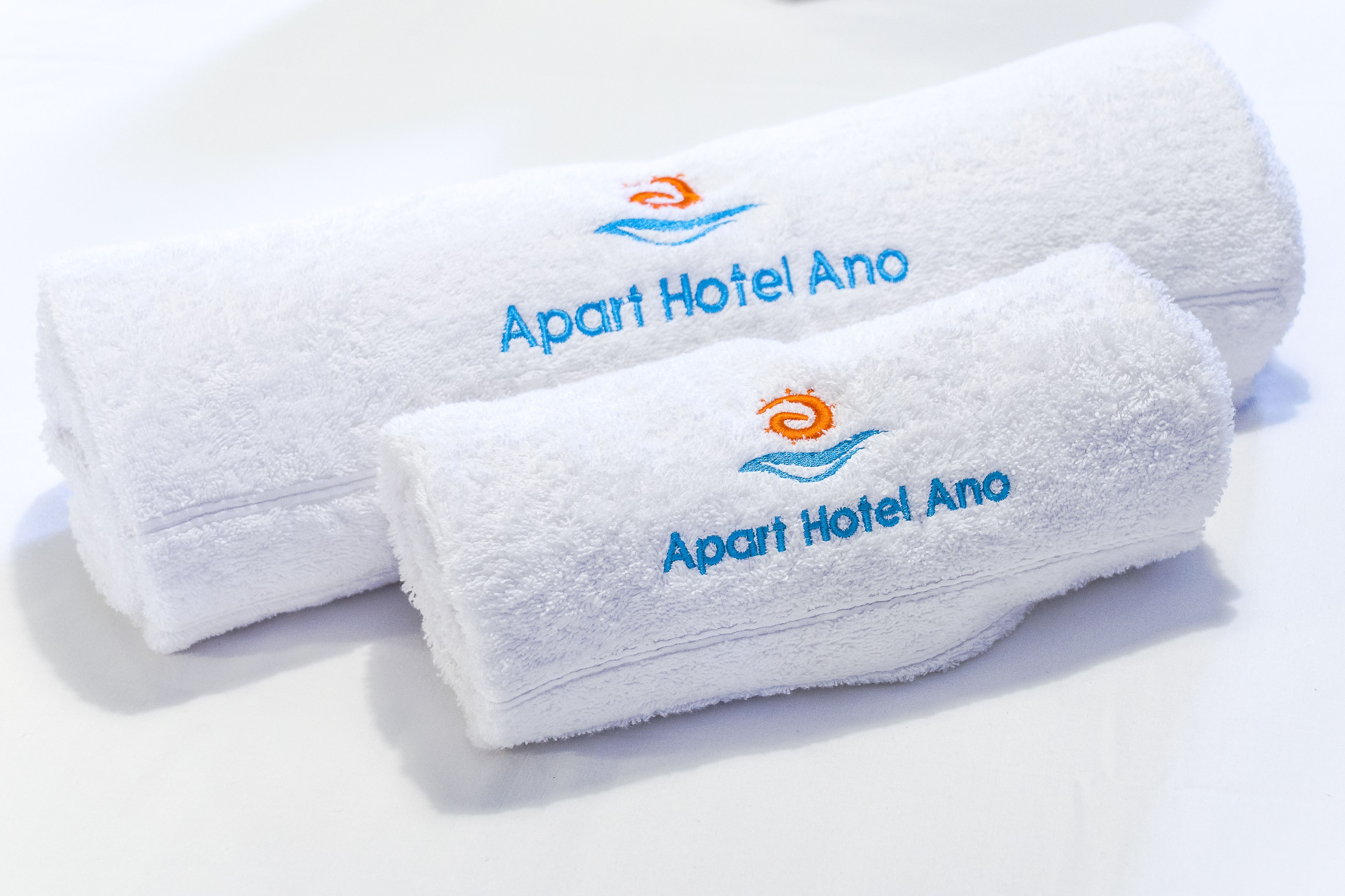 Two rolled white towels with embroidered text and a logo.