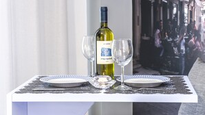 A table with a bottle of wine, two glasses, and a candle. - Ano Aparthotel (Corfu)