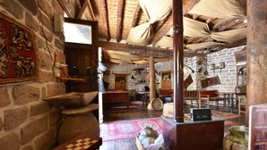 Un interior rústico con paredes de piedra, vigas de madera y un banco a cuadros.