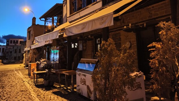 Un edificio con un letrero que dice "Konay Cafe" y un amplio espacio al aire libre con mesas y sillas.