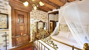Un dormitorio con cama, armario de madera, espejo y alfombra roja estampada.