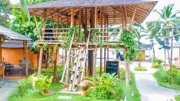 A bamboo structure with a roof, surrounded by greenery and a sign that reads "The wind massage garden".