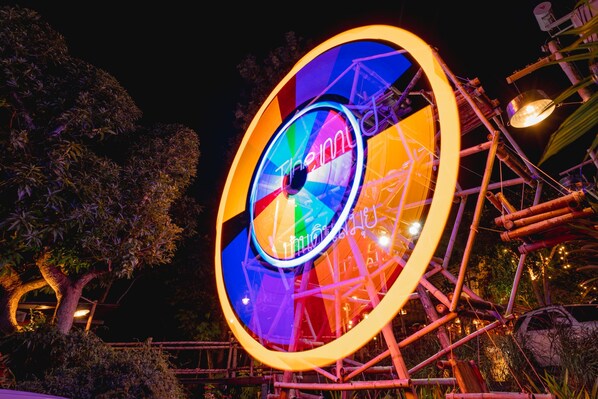A large, colorful circular structure with a central wheel and surrounding scaffolding. - The Mud (Koh Samui)