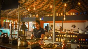 A restaurant interior with a high ceiling, hanging lights, and a variety of kitchen utensils and cookware on display.