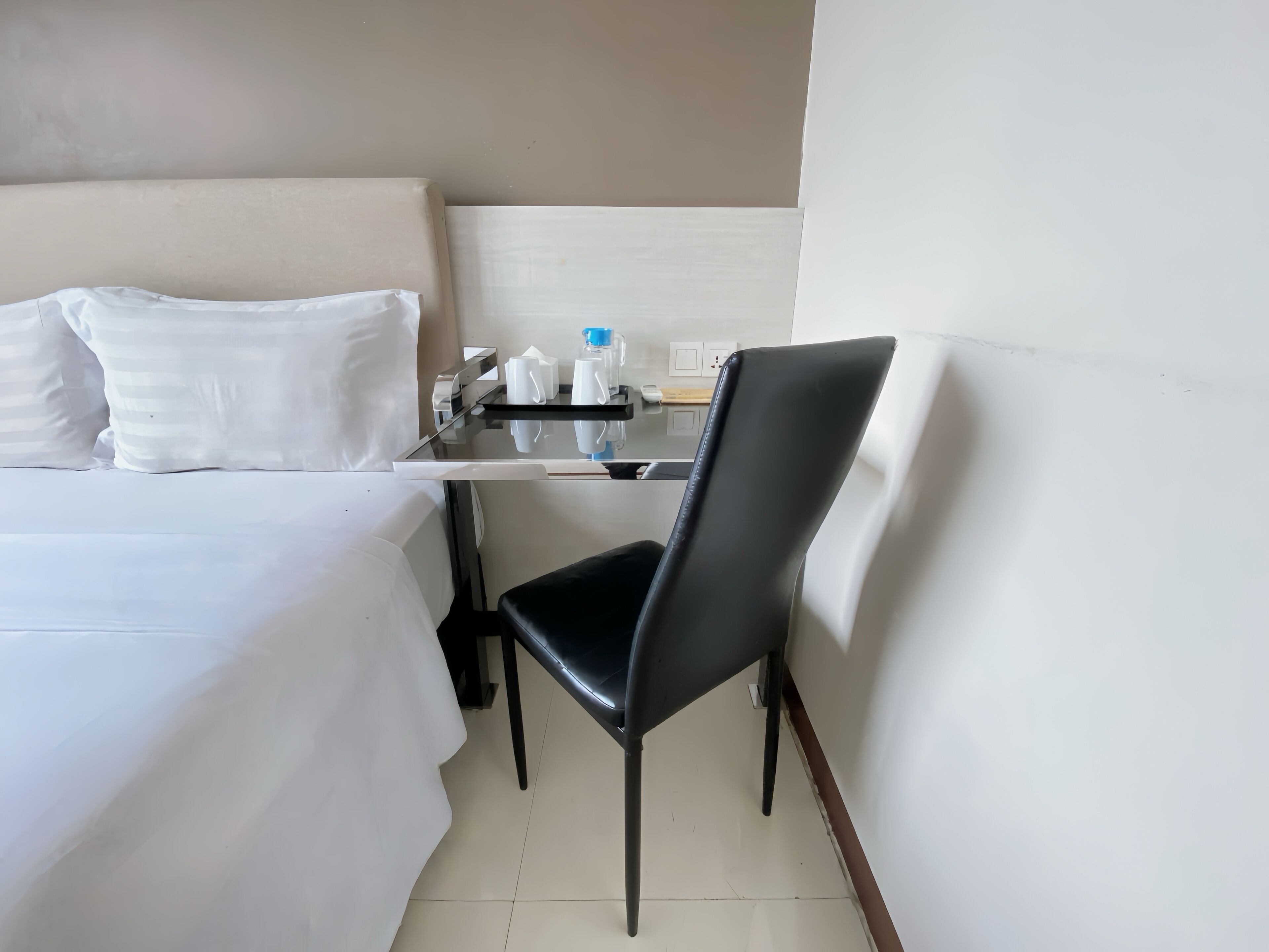Ein Hotelzimmer mit einem Bett, einem Schreibtisch, einem Stuhl und einem kleinen Tisch mit Toilettenartikeln.