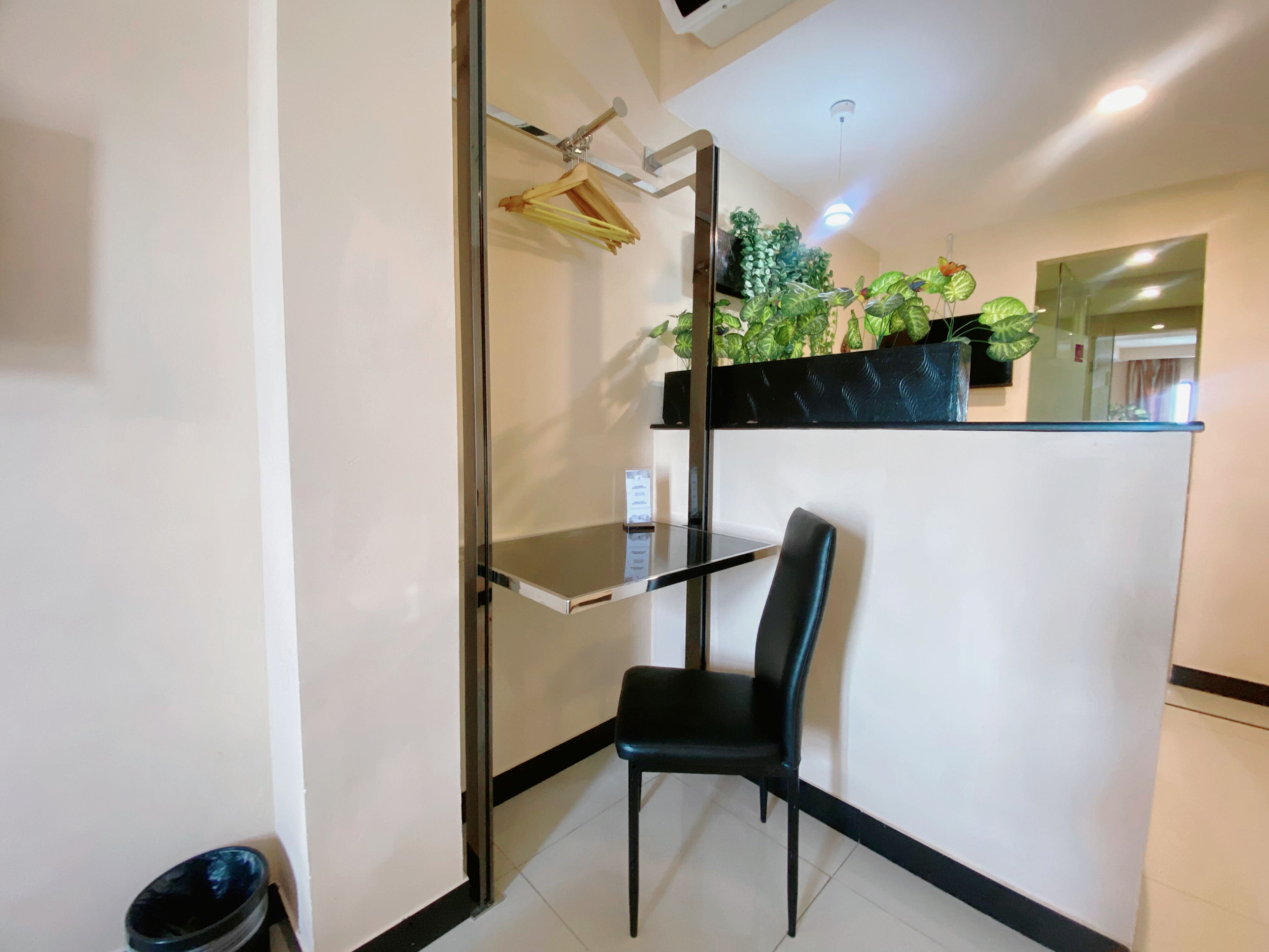 A modern bathroom with a glass shower enclosure, a black chair, and a small shelf.