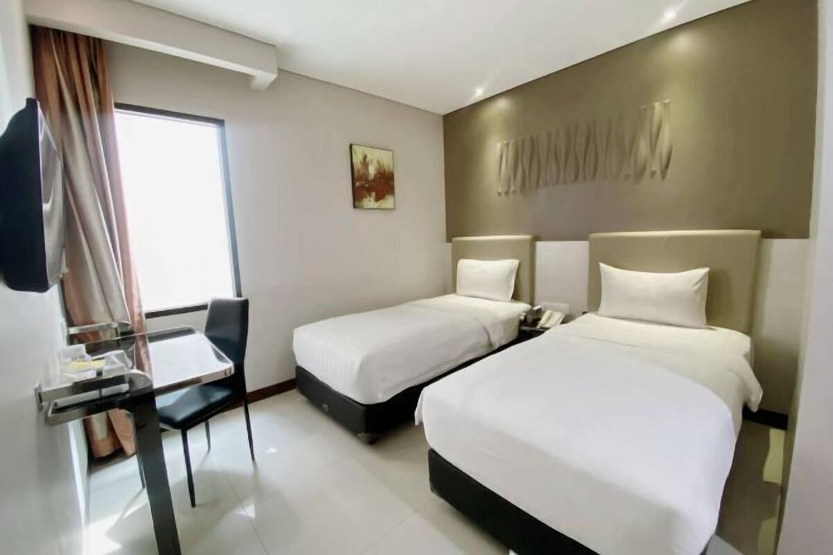 Habitación de hotel con dos camas, un escritorio y una silla.