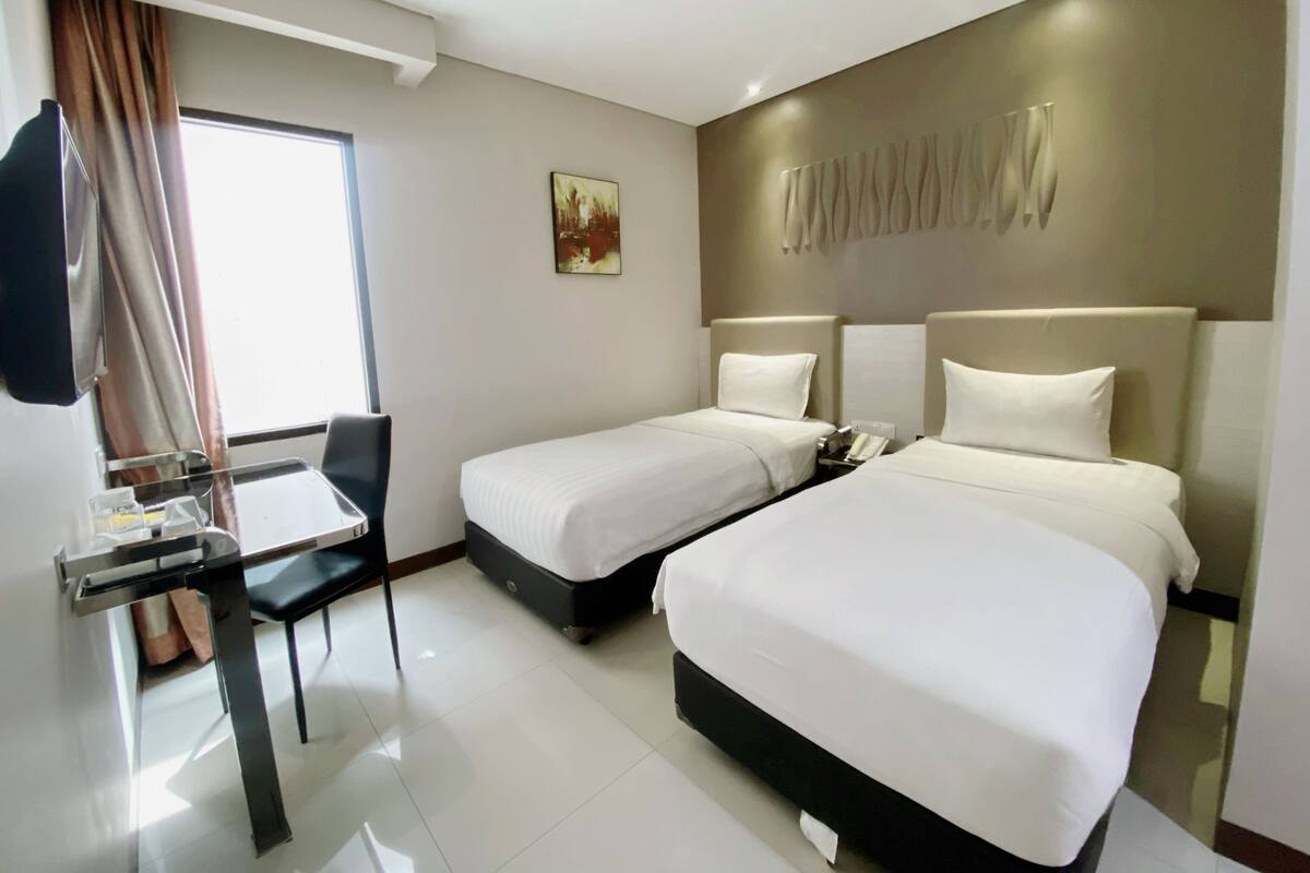 Una habitación de hotel con dos camas, un escritorio y una silla.