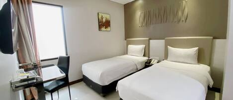 Una habitación de hotel con dos camas, un escritorio y una silla.