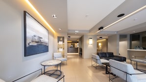 A modern hotel lobby with a large abstract painting, comfortable seating areas, and a reception desk in the background.