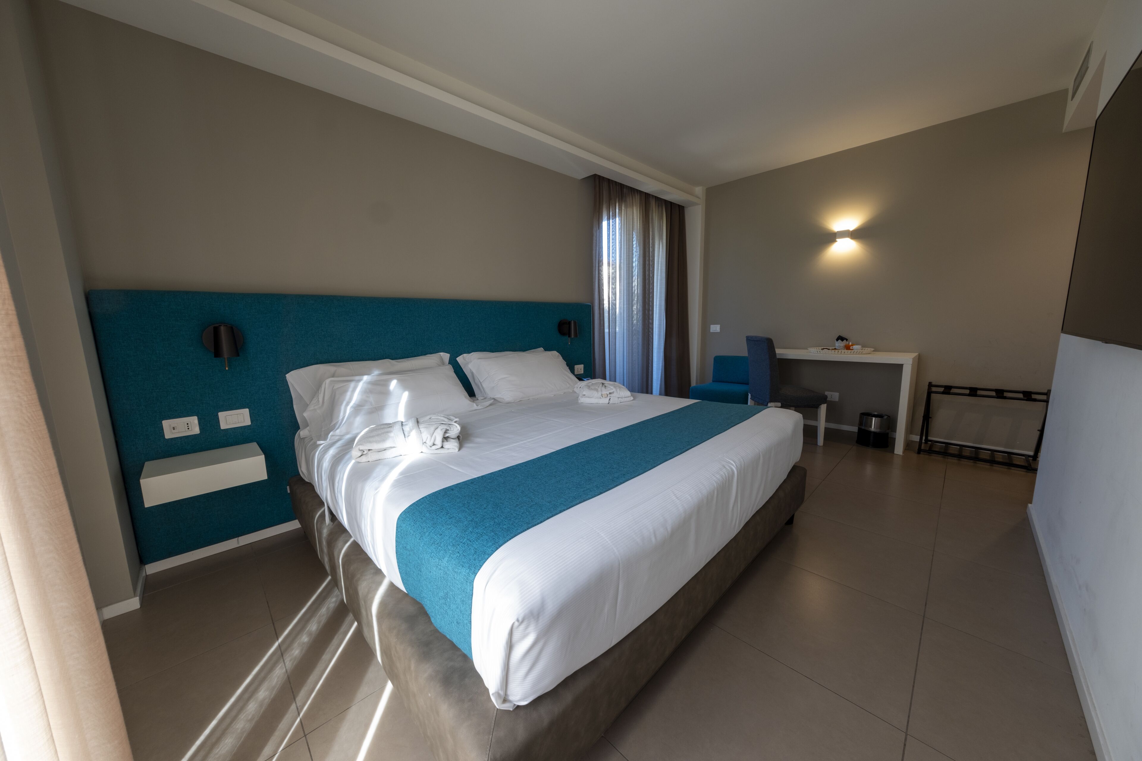 Een hotelkamer met een groot bed, een bureau en een stoel.