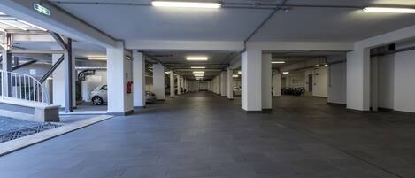 Un aparcamiento amplio y bien iluminado con varios niveles y una escalera central.