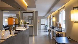 A modern hotel lobby with a reception desk, seating area, and large windows.