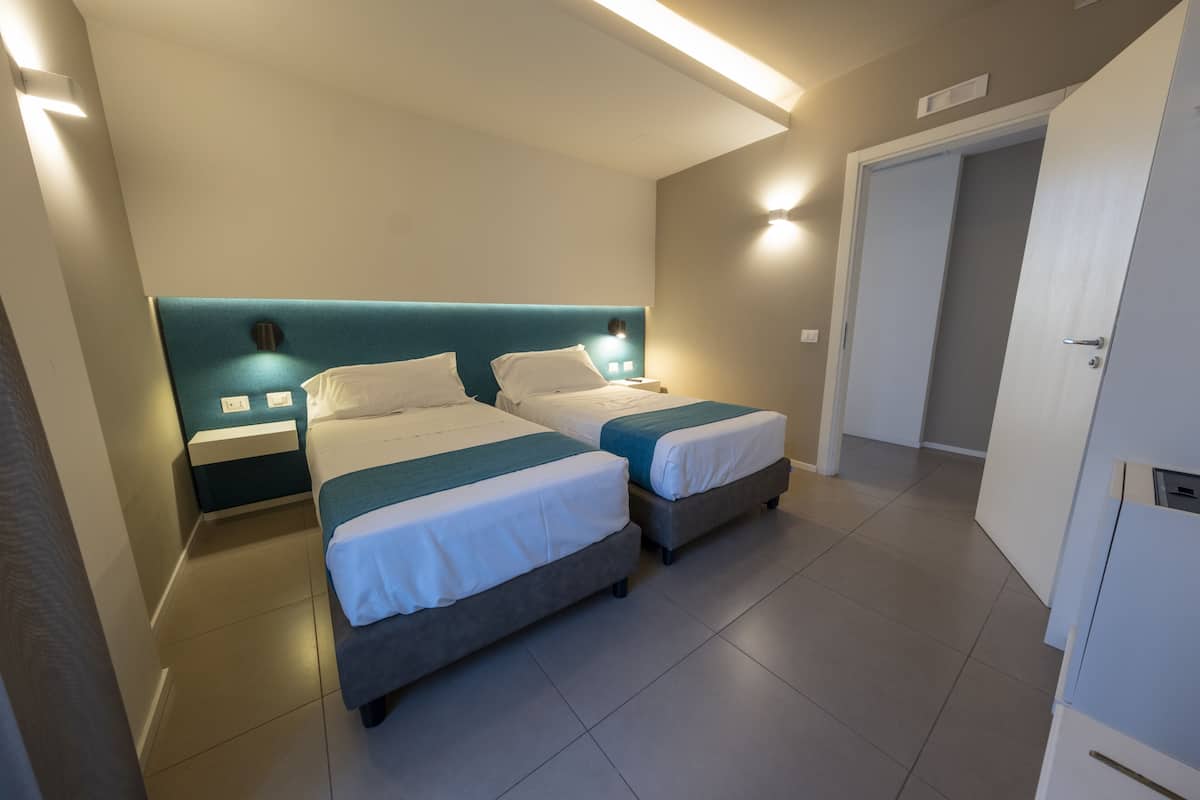 Ein Hotelzimmer mit zwei Betten, einem Kleiderschrank und einem Badezimmer.