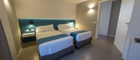A hotel room with two beds, a wardrobe, and a bathroom.
