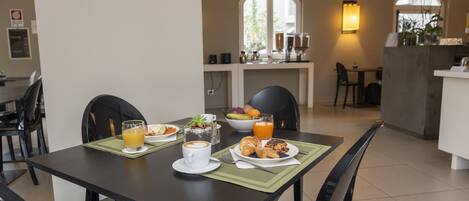 A dining area with a table set for breakfast, including croissants, a coffee cup, and orange juice.