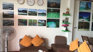 Een woonkamer met een zithoek, een ventilator en wandklokken.