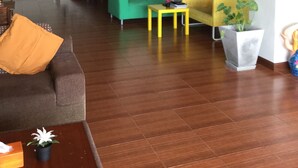 Een woonkamer met een groene bank, een gele bank, een bruine bank en een houten salontafel. Er is een trap die naar een ander niveau leidt.