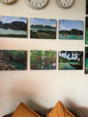 Una pared con seis fotografías enmarcadas que muestran diversos paisajes naturales y un reloj encima.