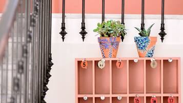 A wall-mounted calendar with numbered slots, two potted plants, and a metal railing.
