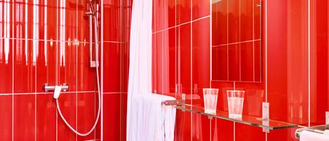 Une salle de bain moderne avec des carreaux rouges, une douche en verre, un lavabo blanc et un miroir avec éclairage intégré.
