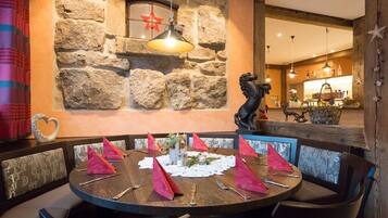 Comedor con pared de piedra, una estatua y una mesa redonda para cuatro comensales.