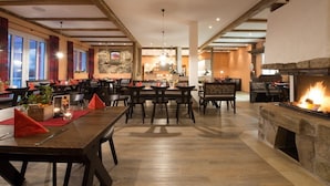 A spacious dining area with wooden tables and chairs, a stone fireplace, and large windows with curtains. - Landgasthof Schwarzes Ross Gmbh & Co. KG (Ansbach)