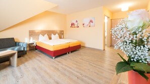 A hotel room with a bed, a sofa, a nightstand, and a wooden floor. - Landgasthof Schwarzes Ross Gmbh & Co. KG (Ansbach)