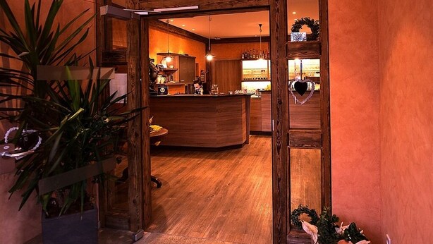 A hotel lobby with a wooden reception desk, a large potted plant, and a heart-shaped decoration on the wall. - Landgasthof Schwarzes Ross Gmbh & Co. KG (Ansbach)