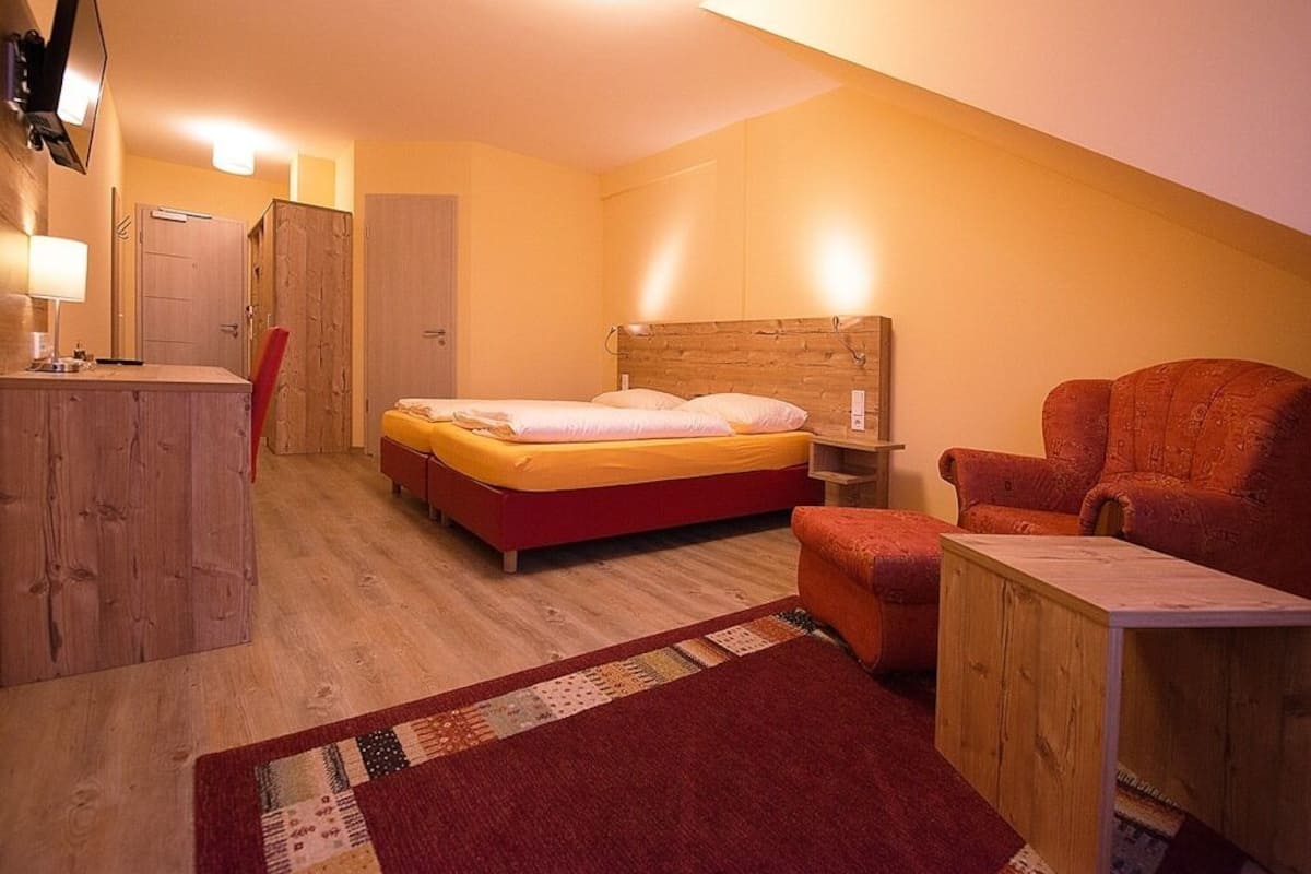 Quarto com cama, escrivaninha, cadeira e guarda-roupa de madeira.