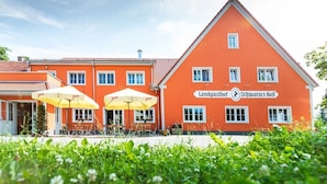 A red building with the sign "Landgasthof Schwarzers Rof" and outdoor seating with yellow umbrellas. - Landgasthof Schwarzes Ross Gmbh & Co. KG (Ansbach)