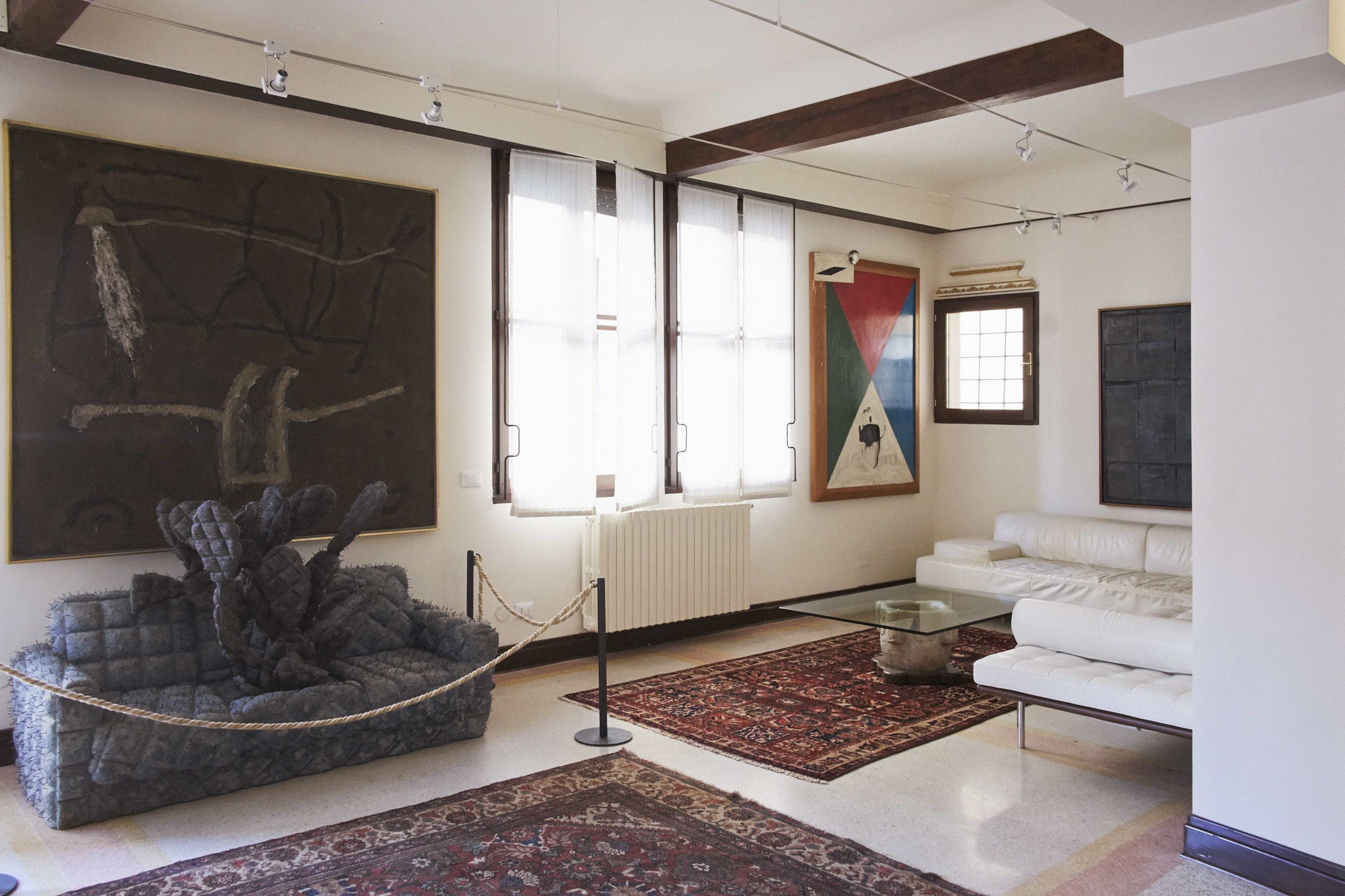 A modern living room with a large abstract painting, a white sofa, and a unique seating area.