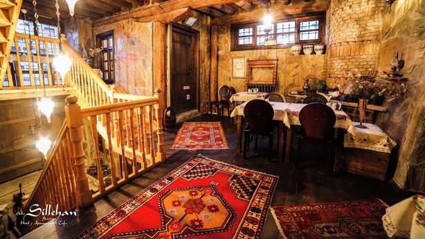 Un interior rústico con vigas de madera, una escalera y un comedor con mesas y sillas.