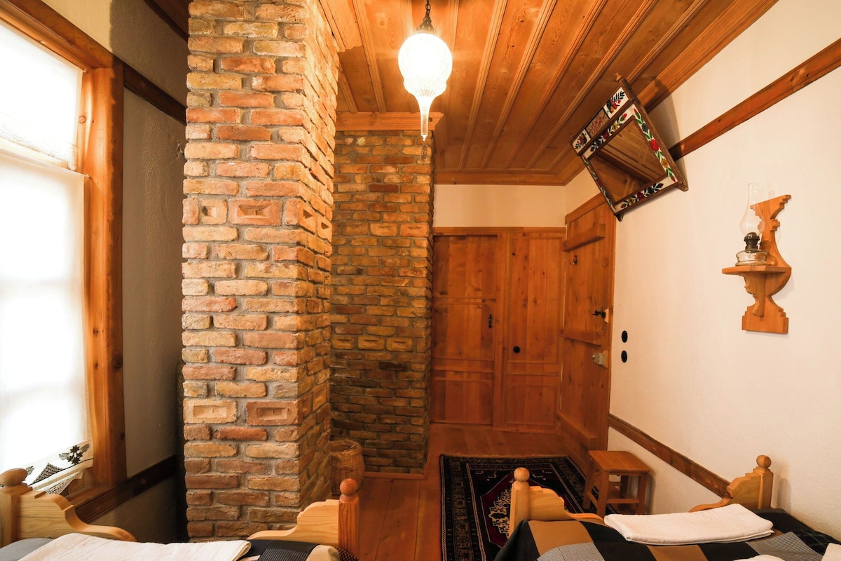 A cozy room with a brick wall, wooden ceiling, and a bed with a patterned bedspread.