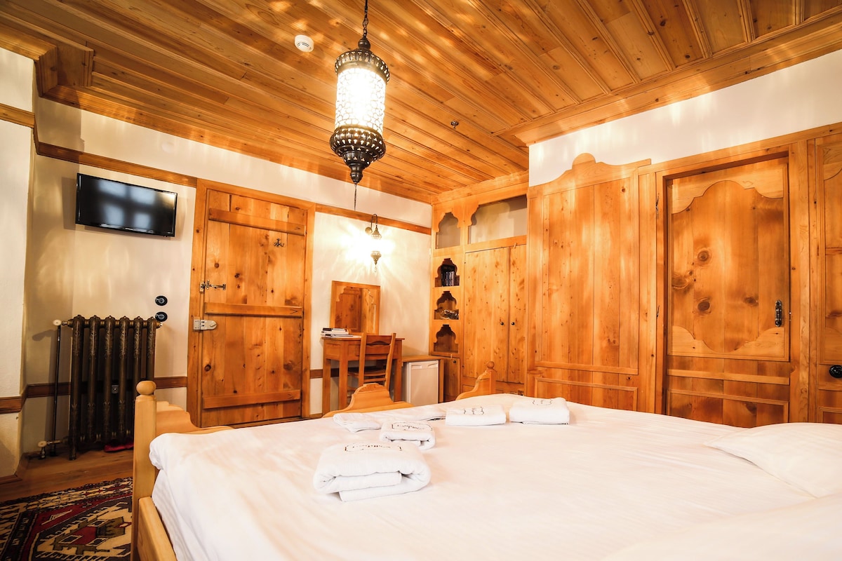 A wooden room with a bed, a television, and a desk.