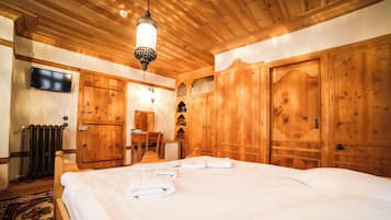 A wooden room with a bed, a television, and a desk.