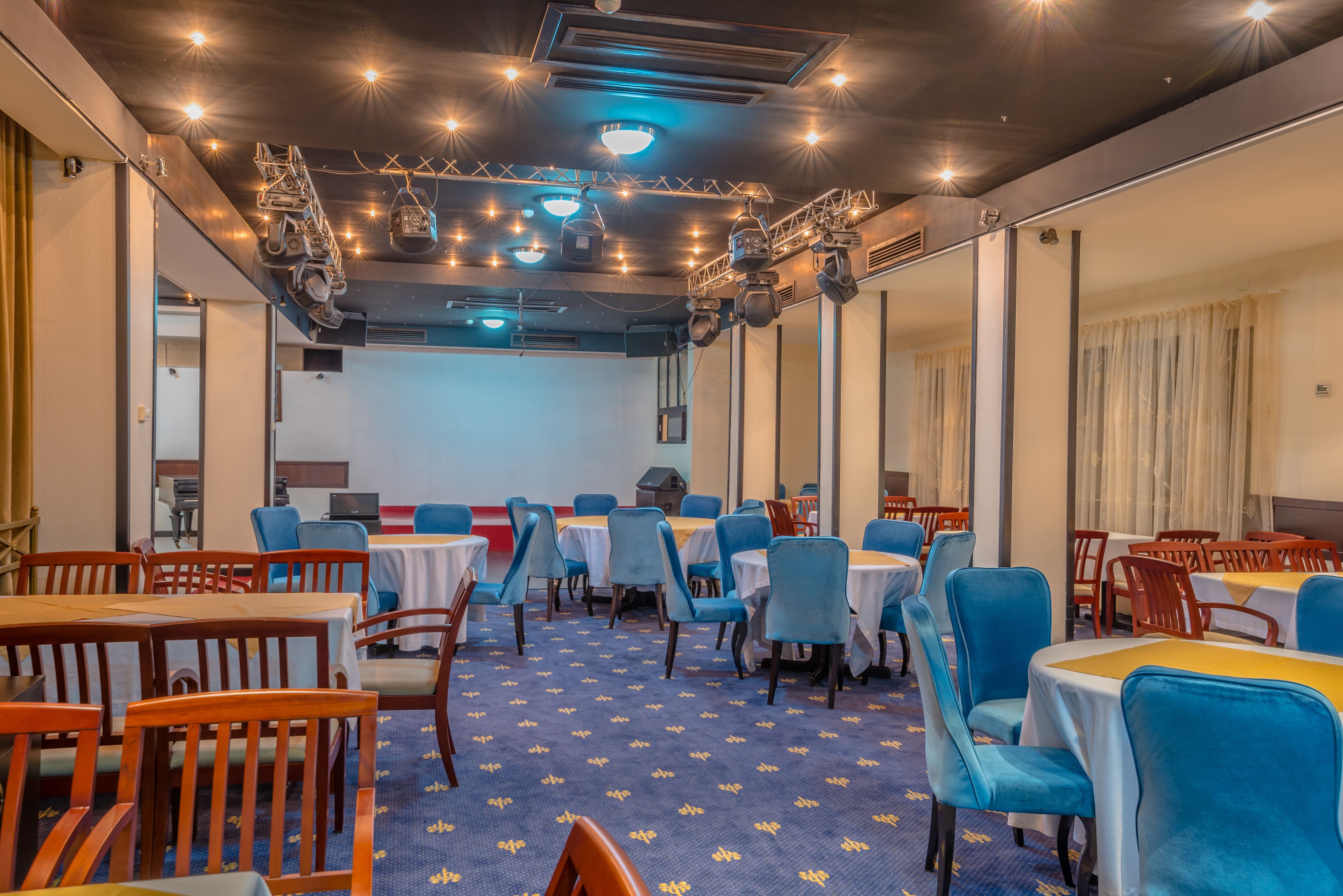 A conference room with tables and chairs, a patterned carpet, and ceiling lights.