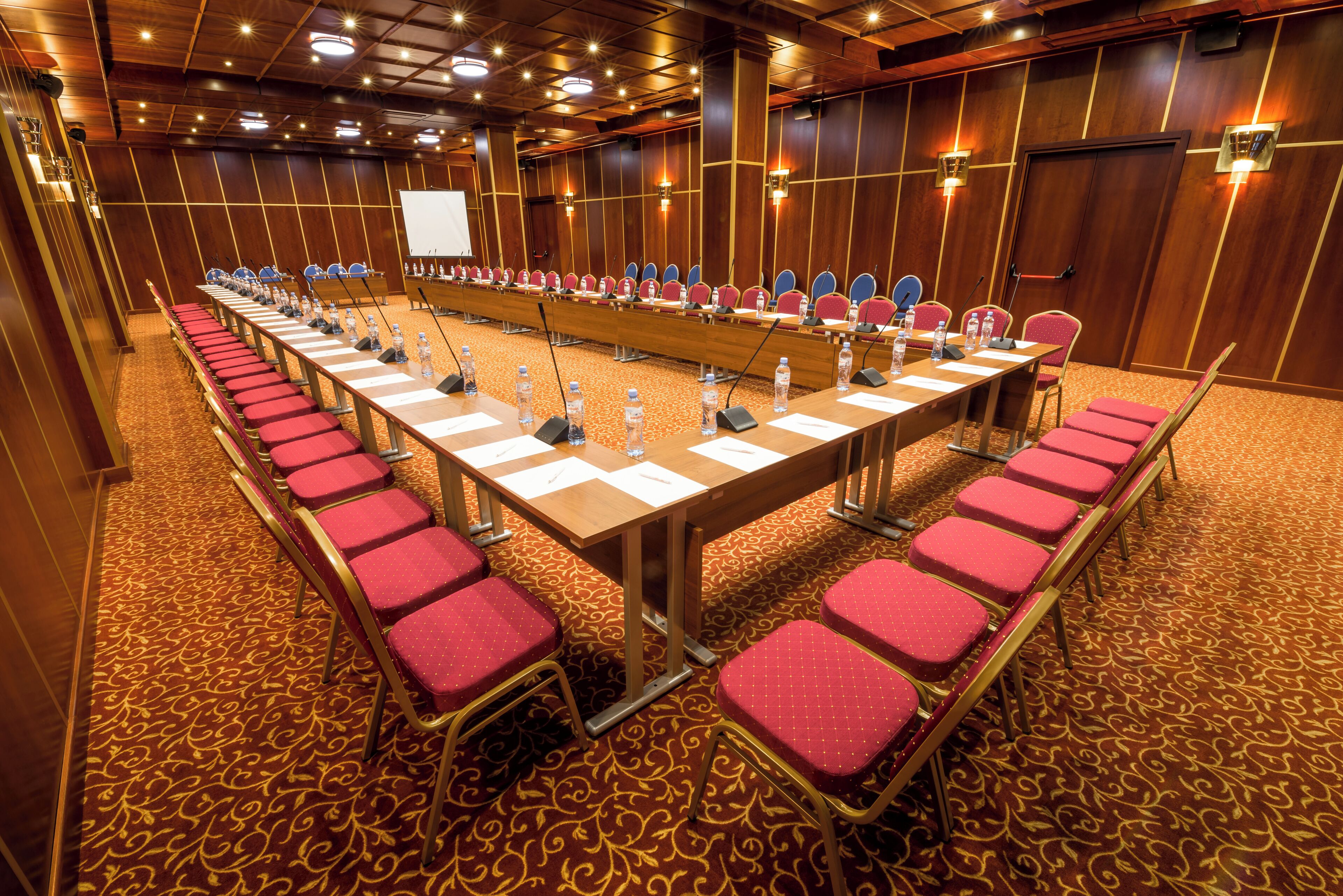 A conference room with a long table, red chairs, and a whiteboard.